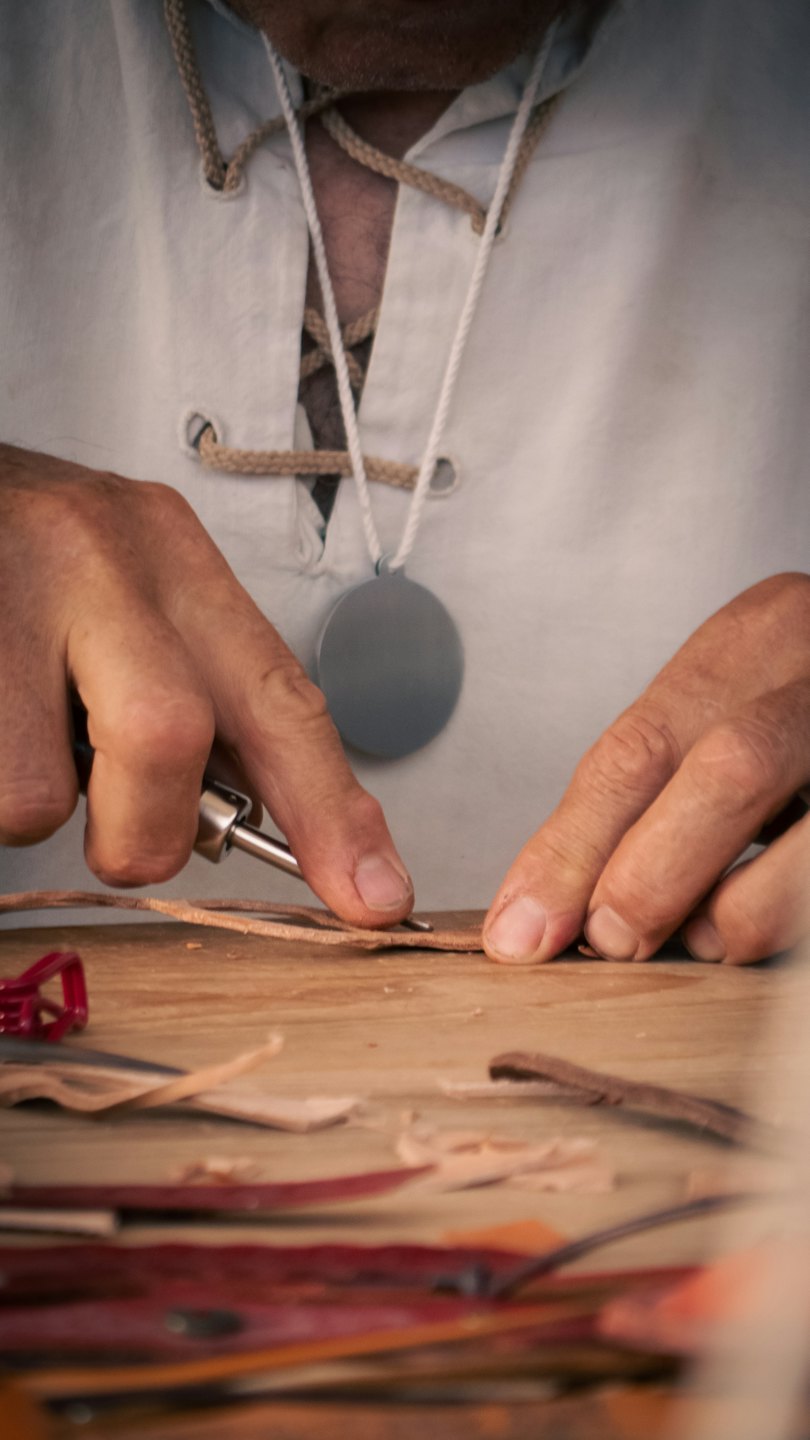Craftsman using a tool to work on leather in a workshop.