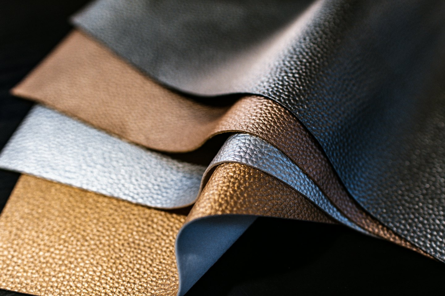 Metallic textured fabric samples in grey, bronze, silver, and gold.