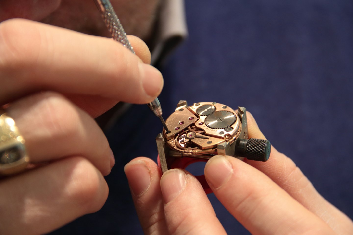 Watchmaker uses a fine tool to repair mechanical watch gears.