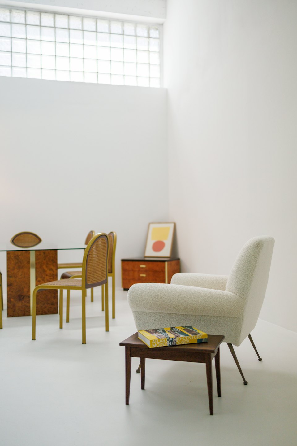 Cream bouclé armchair next to a dark wood table with a book.